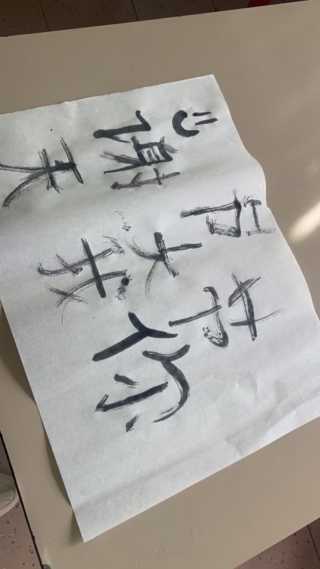 Carta da calligrafia con caratteri cinesi eseguiti a mano da studenti italiani.